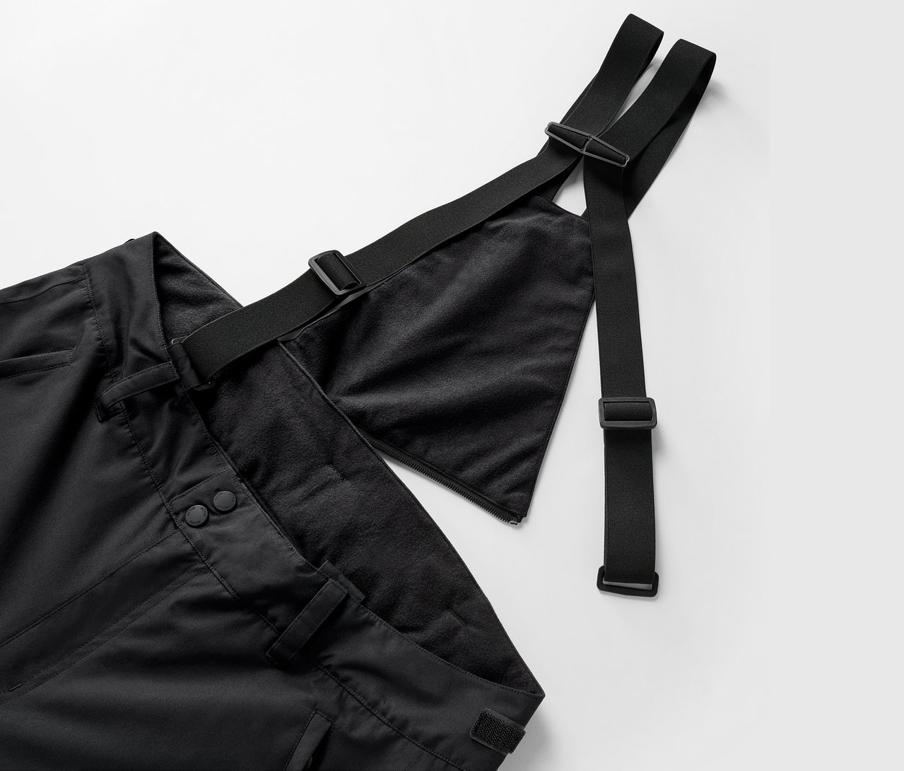 Nagyított kép egy fekete kantáros nadrágról, állítható pántokkal.
