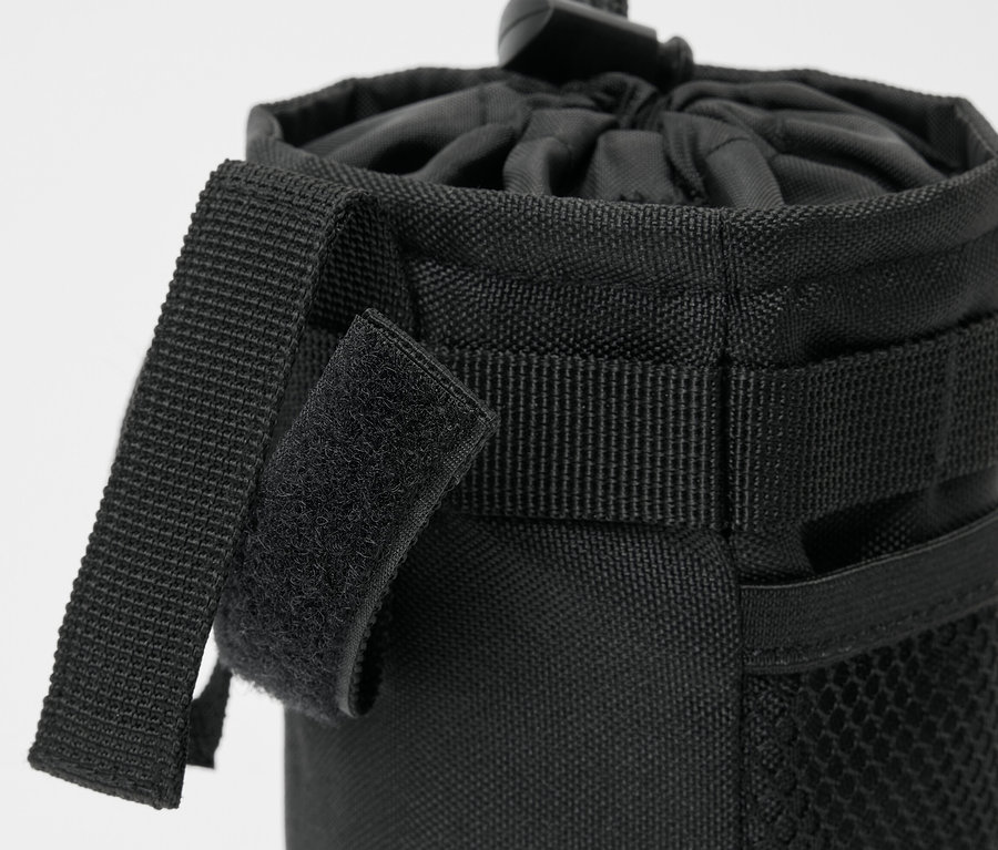 Egy fekete kerékpárra való uzsonnástáska részlete, húzózsinórral és tépőzáras pántokkal.