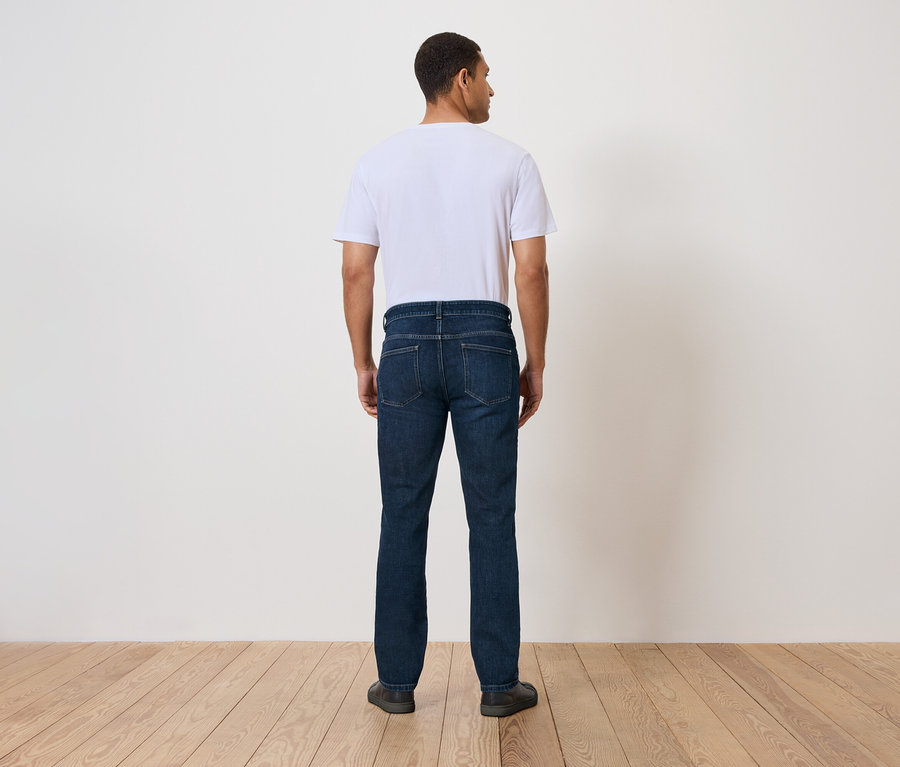 Egy férfi háttal áll a kamerának, farmerben és pólóban.