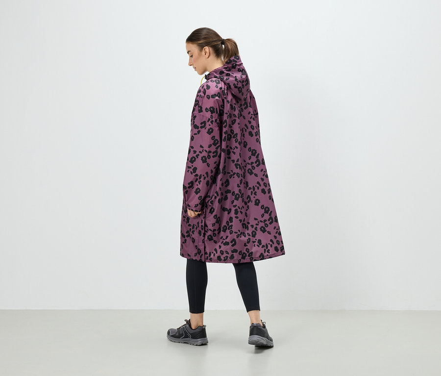 Egy nő lila, fekete állatmintás kabátot, fekete leggingst és szürke tornacipőt visel.