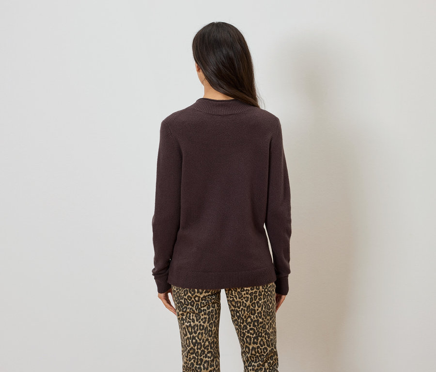 Hátulnézet egy hosszú, sötét hajú nőről, aki sötétbarna pulóvert és leopárdmintás nadrágot visel.