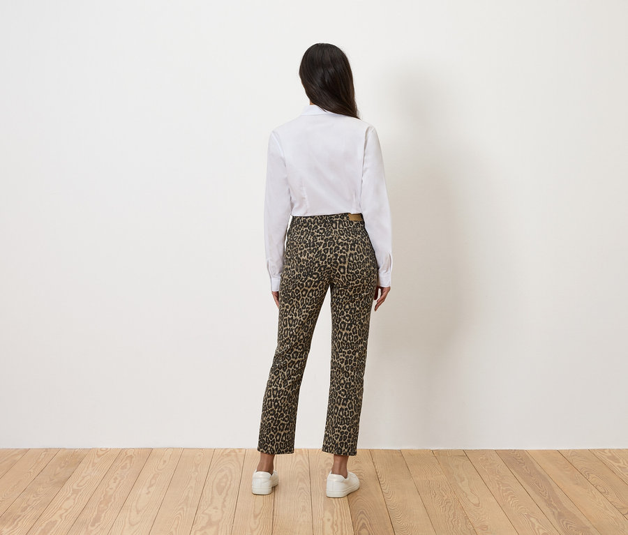 Hátulnézetből egy nő fehér ingben és leopárdmintás nadrágban.