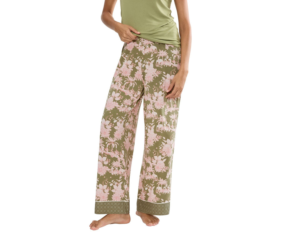 Nő visel egy zöld trikót és egy olívazöld pizsama nadrágot rózsaszín virágmintával.