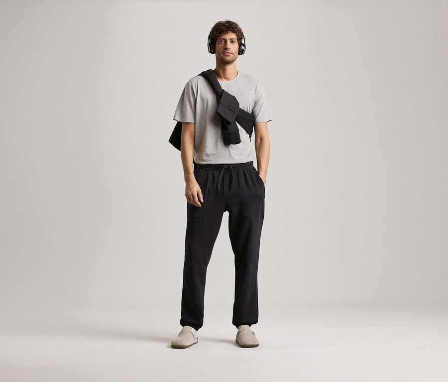 Férfi fejhallgatóval, szürke pólóval és fekete szabadidőnadrággal.