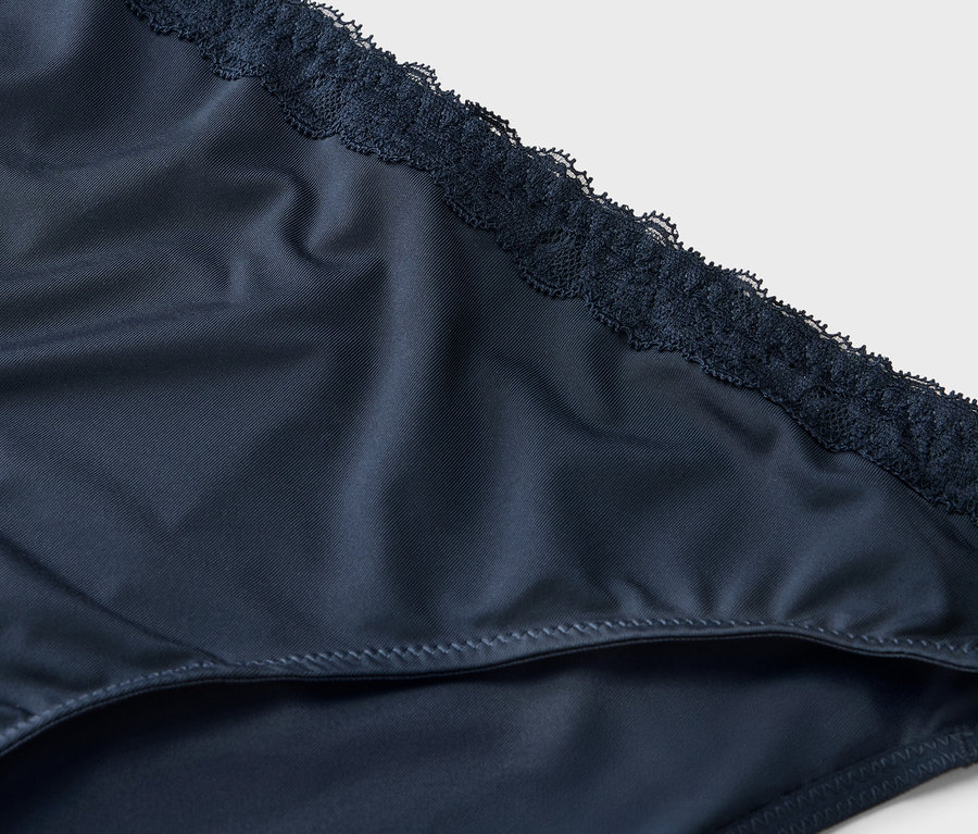 Közeli kép egy sötétkék csipkés női alsóneműről.