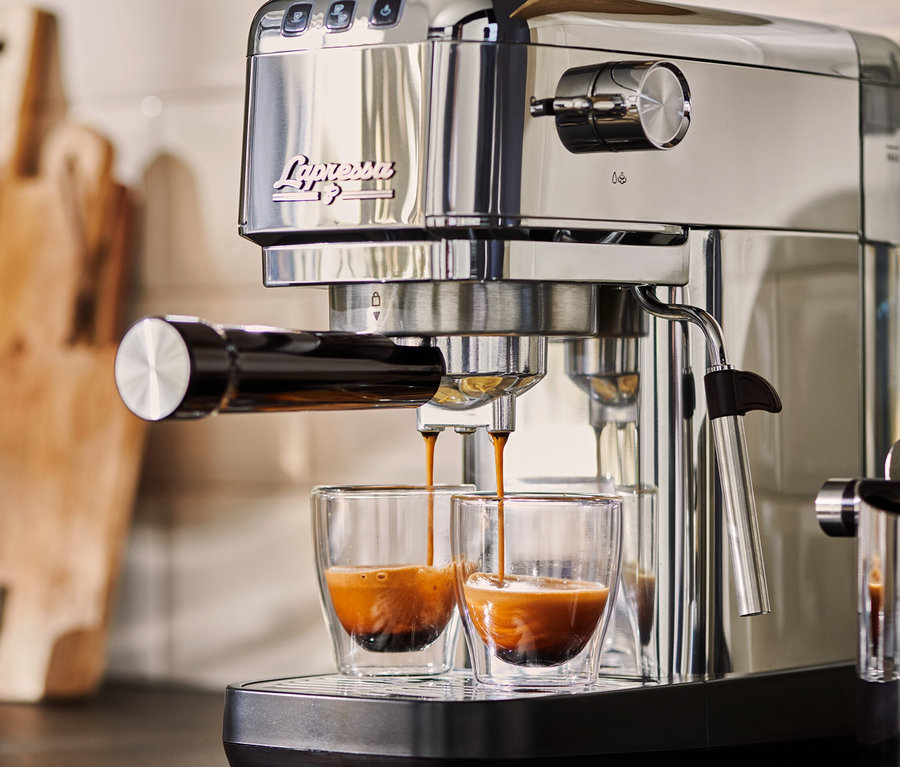 Egy ezüstszínű »Lapressa« karos eszpresszó kávéfőző éppen espressot készít két üvegpohárba.