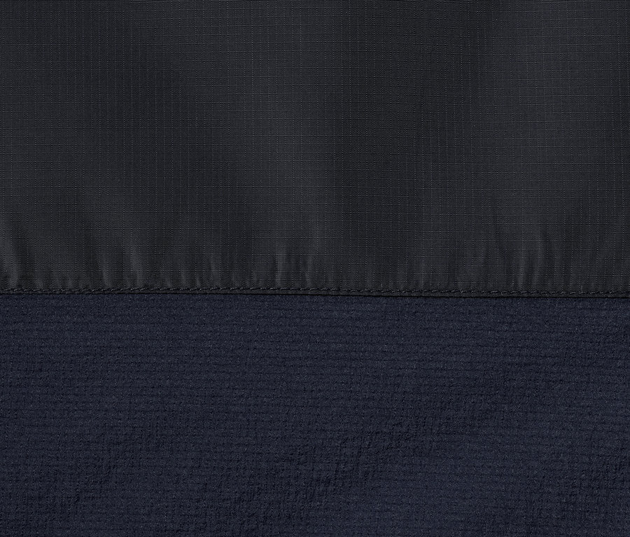 Egy sötétkék, női, könnyű funkcionális kabát részlete.