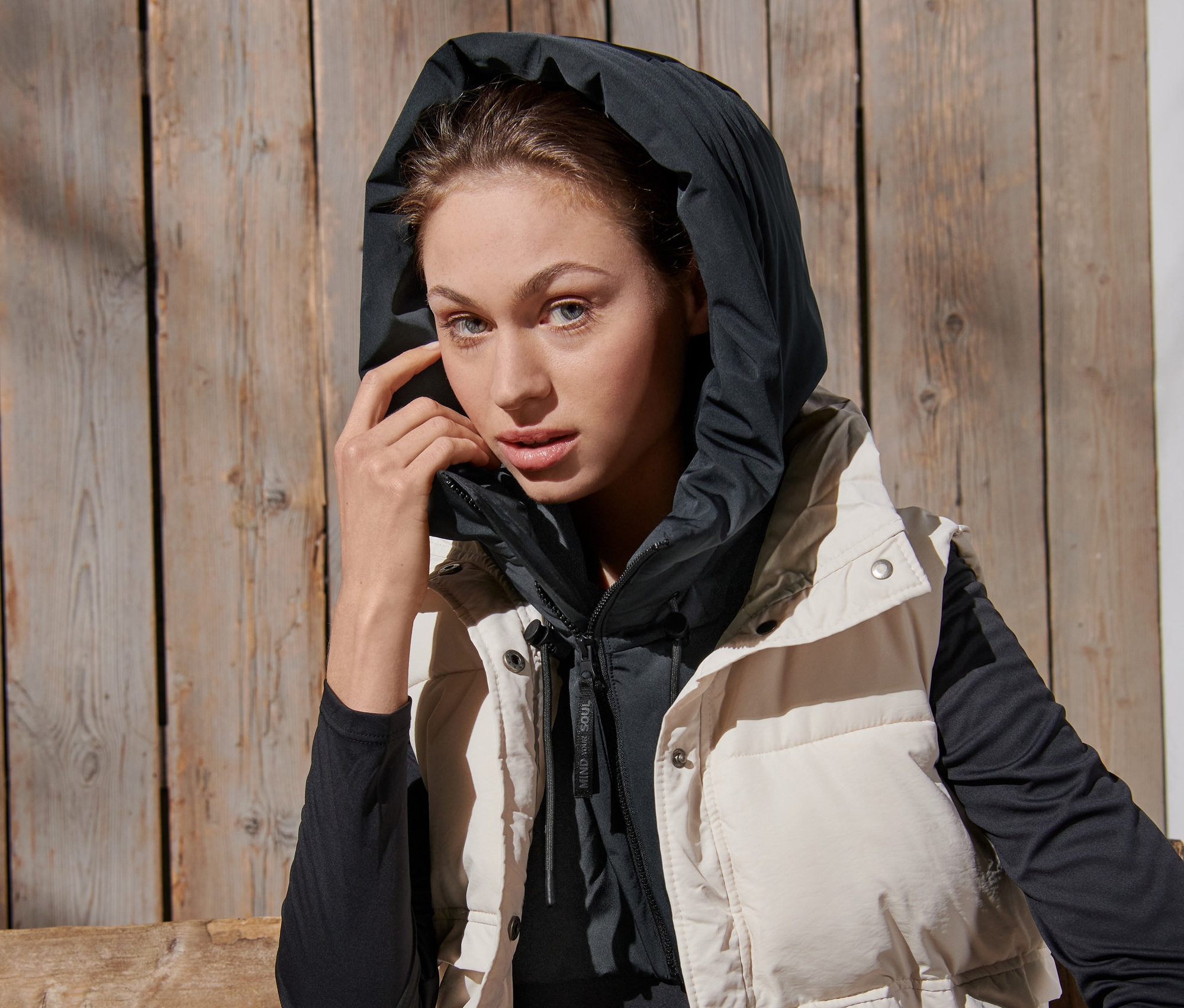 Nő visel steppelt kapucnit állógallérral és mellényt.