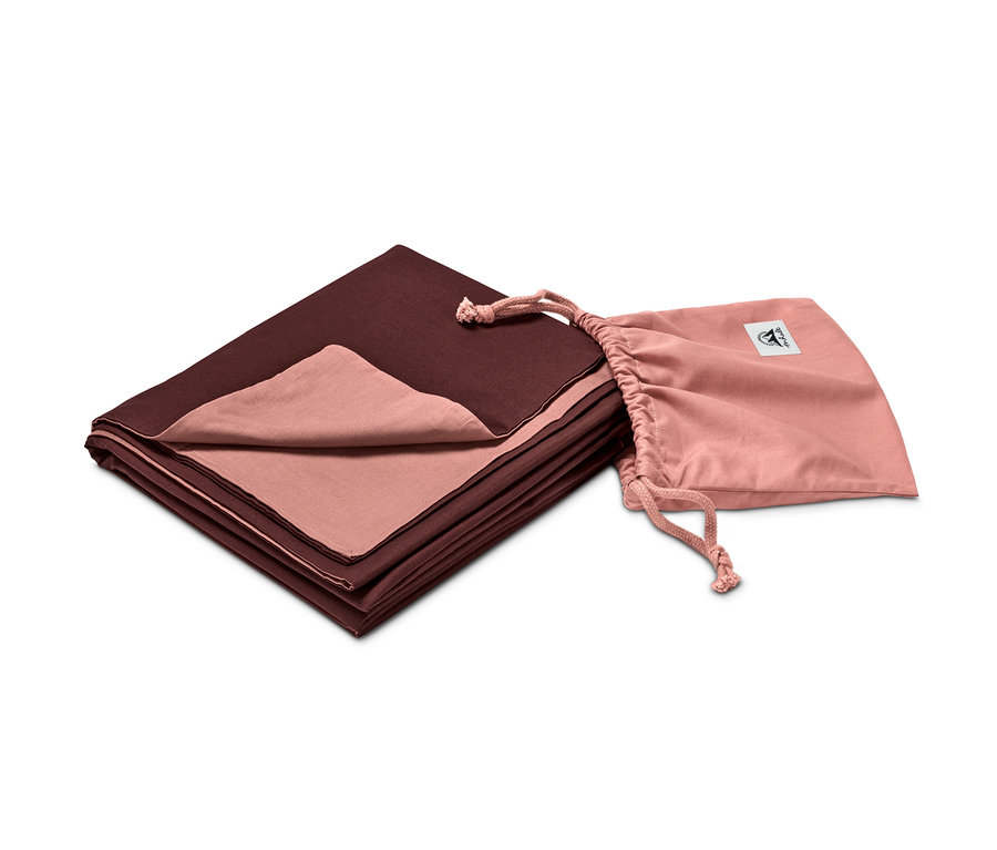 Egy könnyű hálózsák összehajtva egy rózsaszín zsák mellett.