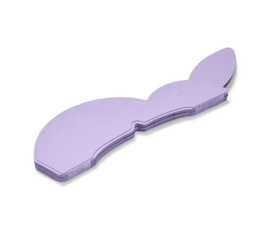 Egy lila papír húsvéti nyúl fekszik egy fehér háttéren.