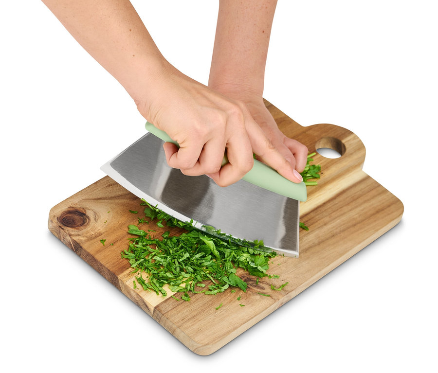 Kezek fűszereket vágnak egy pizza- és fűszervágóval egy fa deszkán.