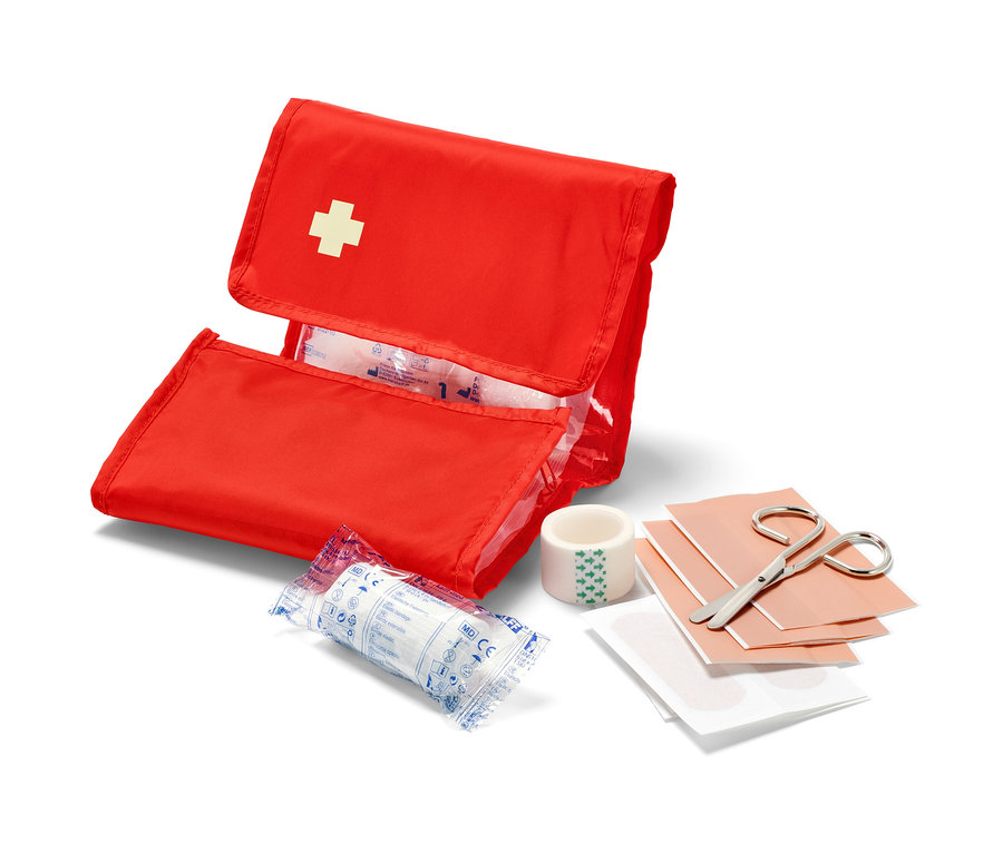 Nyitott piros Elsősegélynyújtó táska fehér kereszttel és tartalommal, például kötszerekkel és ollóval.