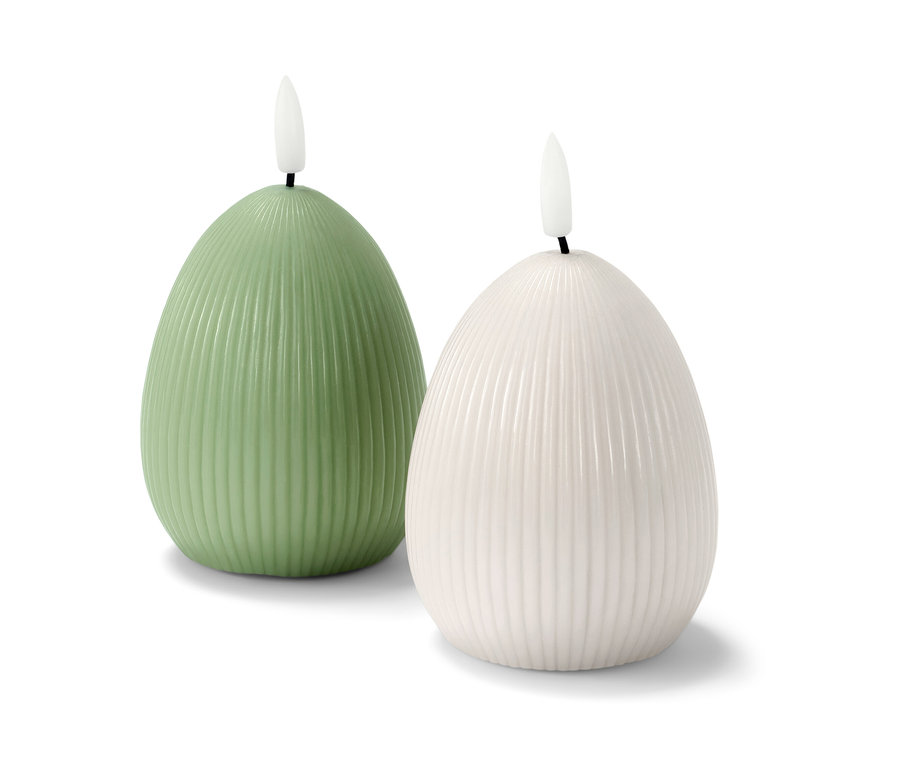 Két LED-es valódi viaszgyertya, egy zöld és egy fehér, egymás mellett állnak fehér háttér előtt.