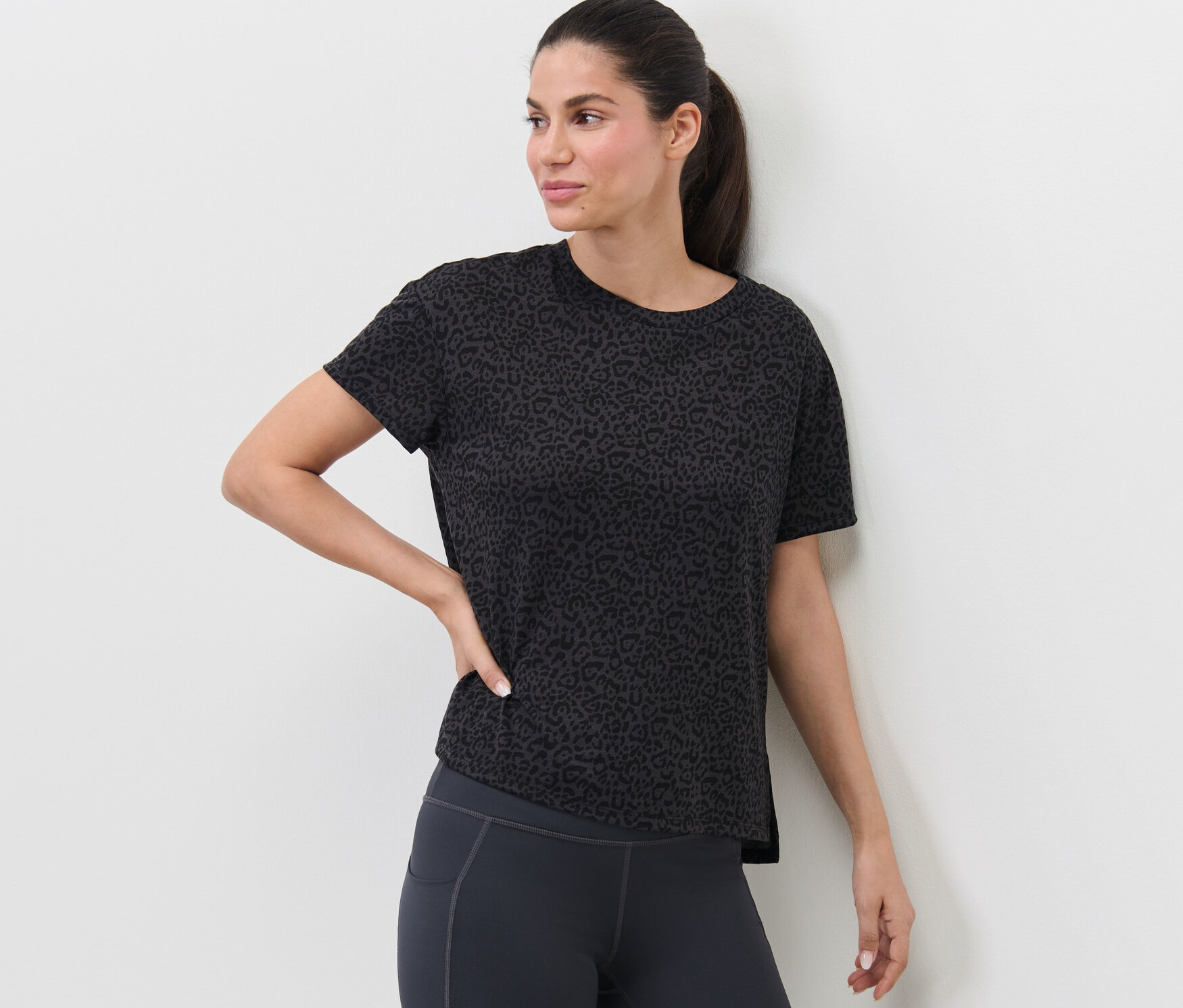 Nő pózol antracit színű sportfelsőben.