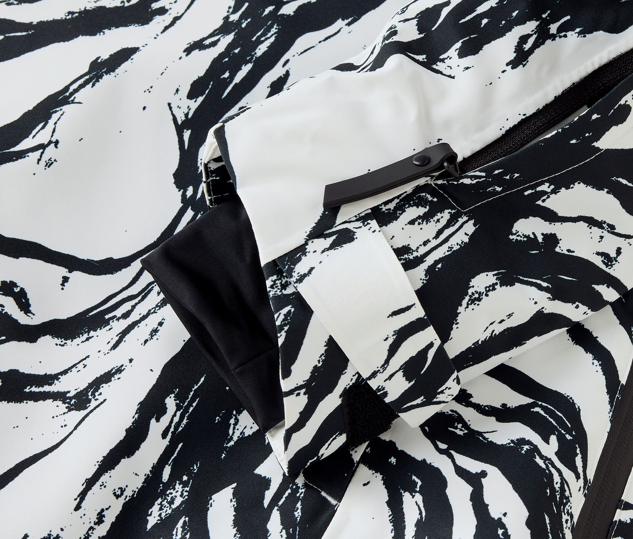 Egy fekete-fehér zebra mintás dzseki részlete, látható ujj és cipzár.