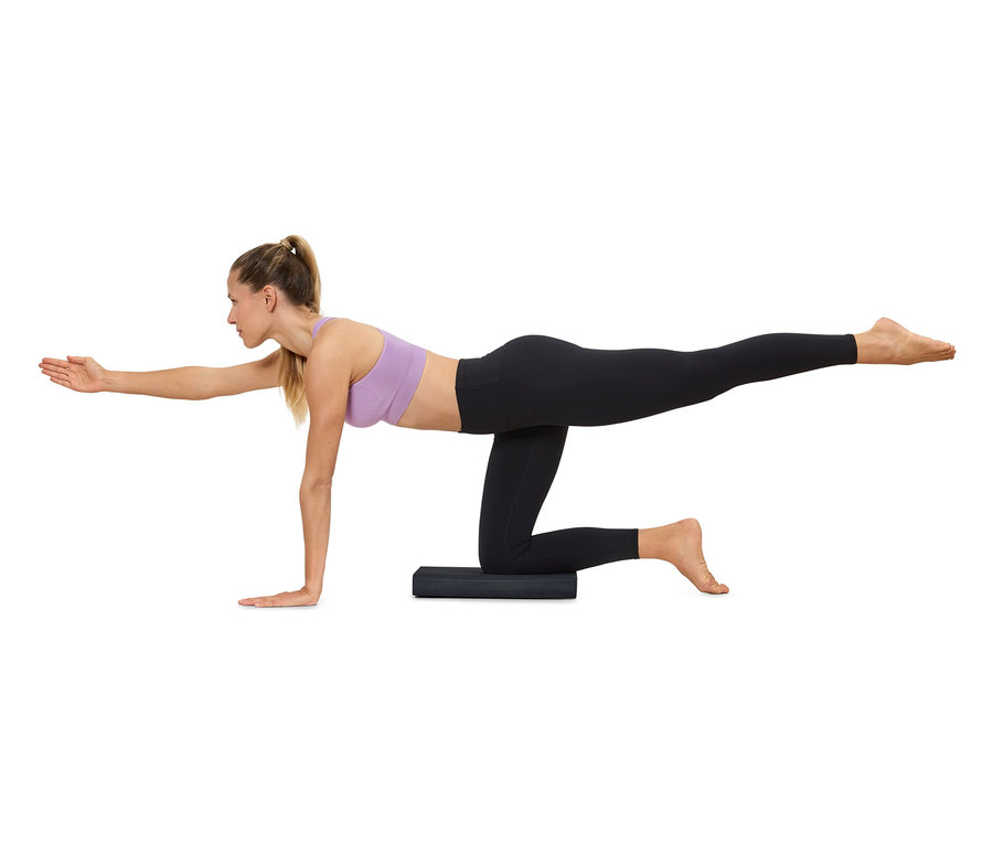 Egy nő jógázik egy matracon, sportruházatot visel.