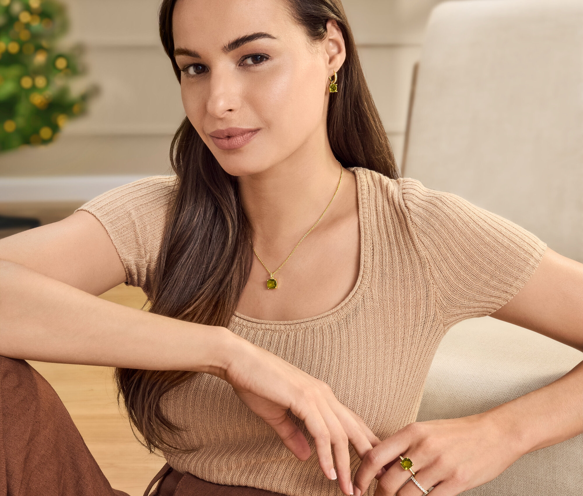 Nő ül nyaklánccal, fülbevalóval és gyűrűvel, zöldesbarna üvegkristály kővel.