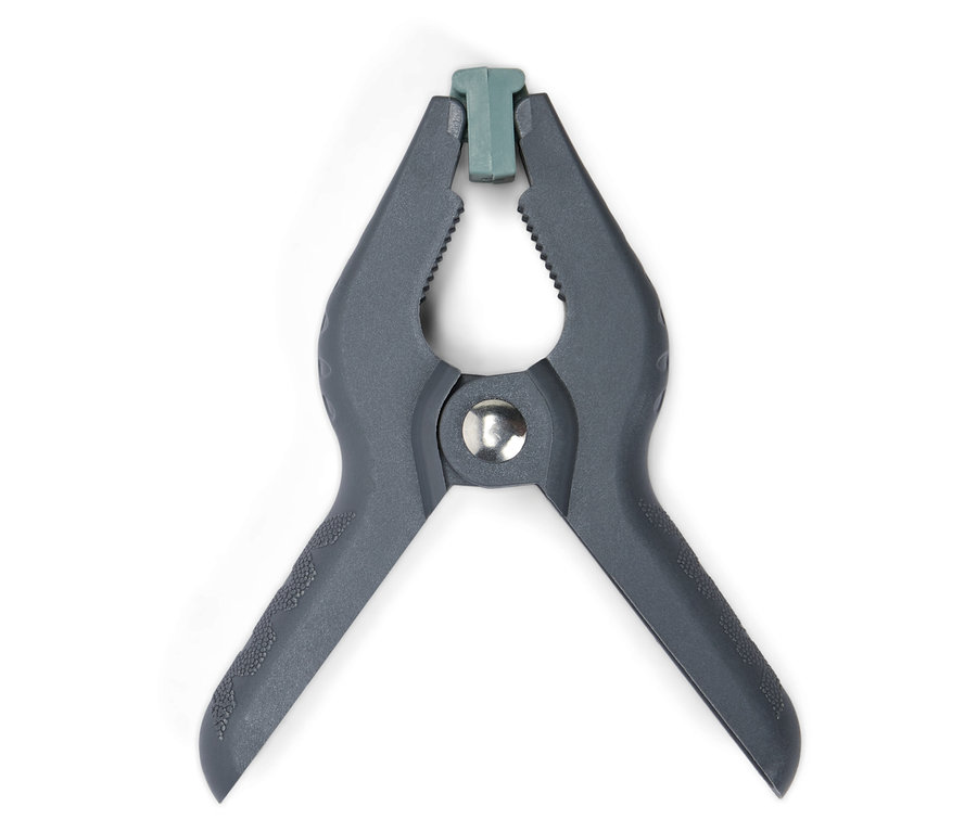 Egyetlen szürke műanyag rugós szorítóelem közeli képe zöld csúccsal, fehér háttérrel.