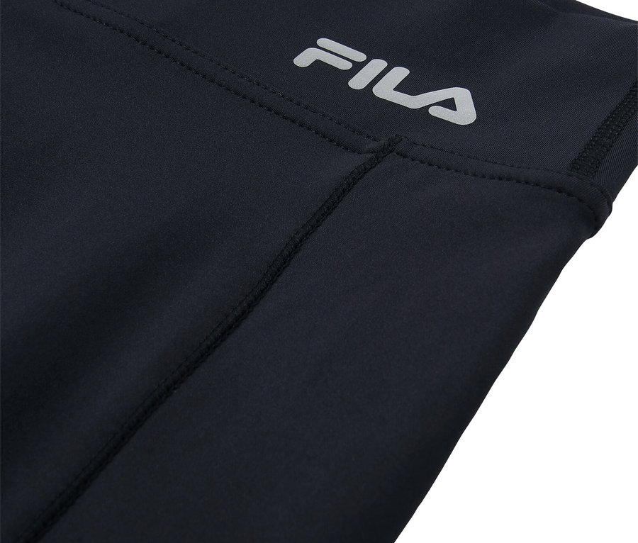 Egy fekete leggings részletfotója ezüst FILA logóval.