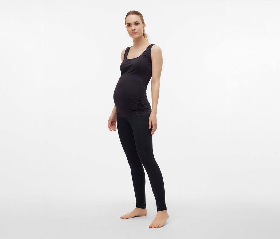 Egy várandós nő fekete MAMALICIOUS kismama topot visel, egységes méretben, leggingsszel.