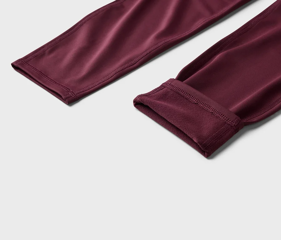 Bordó leggings közeli képe, az egyik szára fel van hajtva, hogy látható legyen a polár bélés.