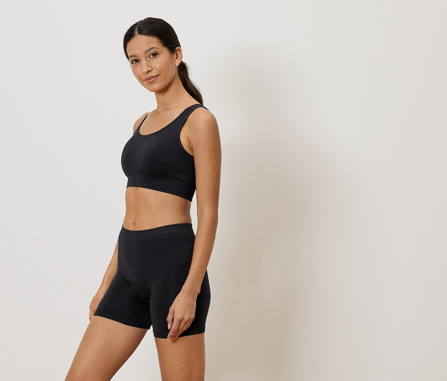Nő visel fekete sportmelltartót és rövidnadrágot.