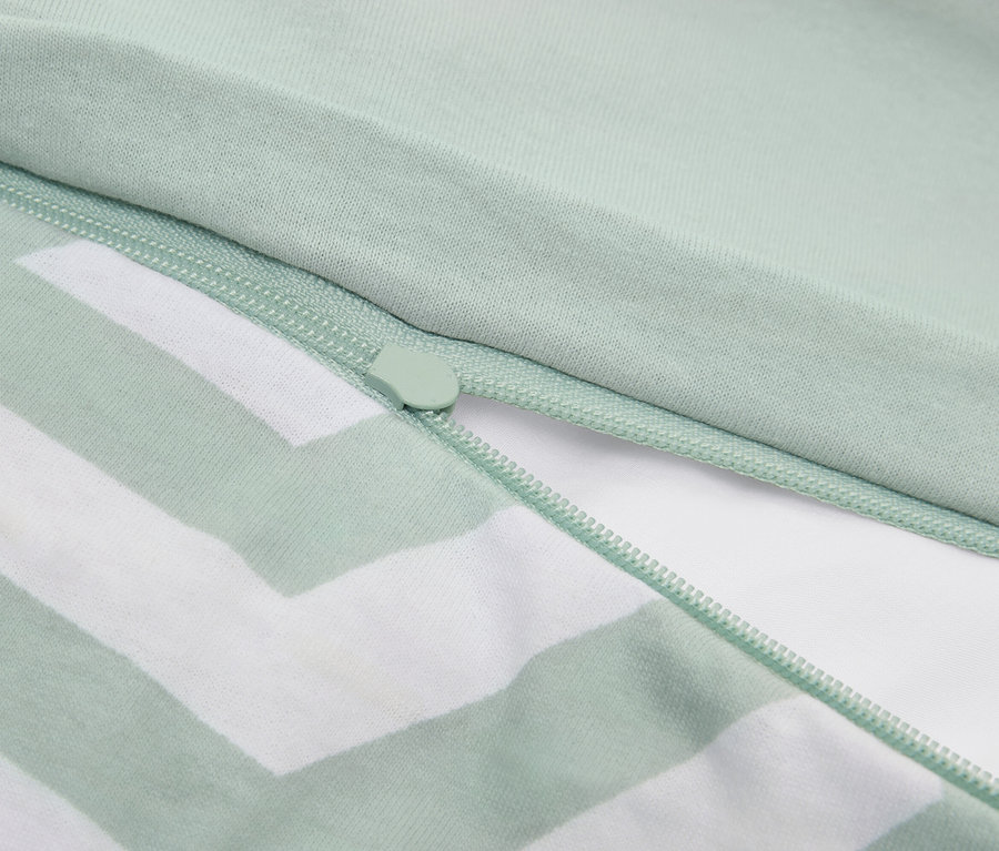 Közeli kép egy világoszöld csíkos párnahuzatról cipzárral.