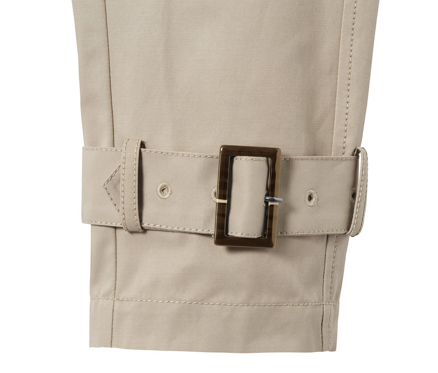 Egy rövid, bézs női ballonkabát részlete övvel és csattal.