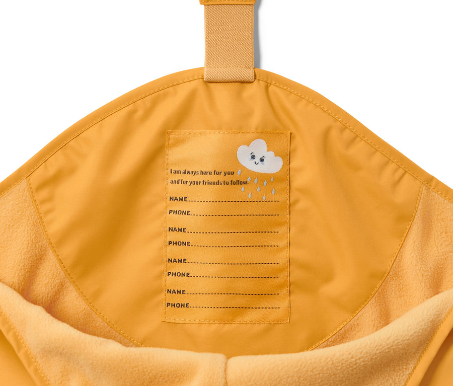 Közeli kép egy kukoricasárga gyerek termo esőnadrág belső oldaláról, rajta név és telefonszám számára fenntartott hellyel.