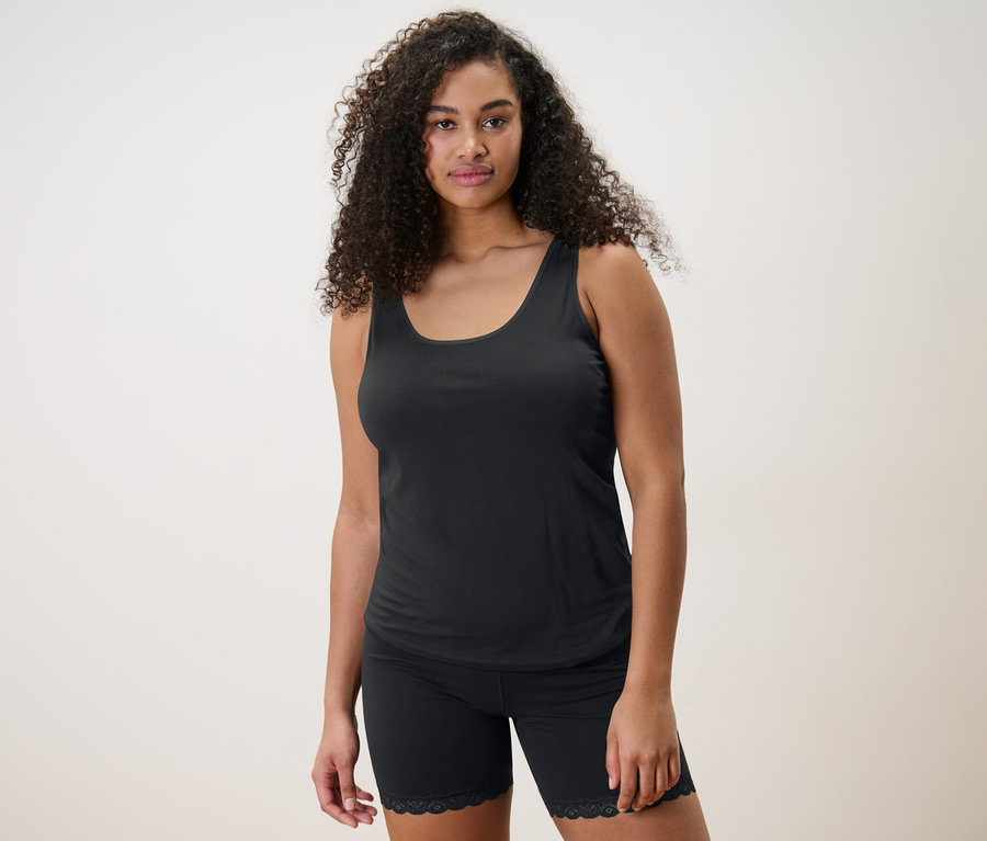 Nő visel fekete trikót és 2 db női kerékpárosnadrágot.