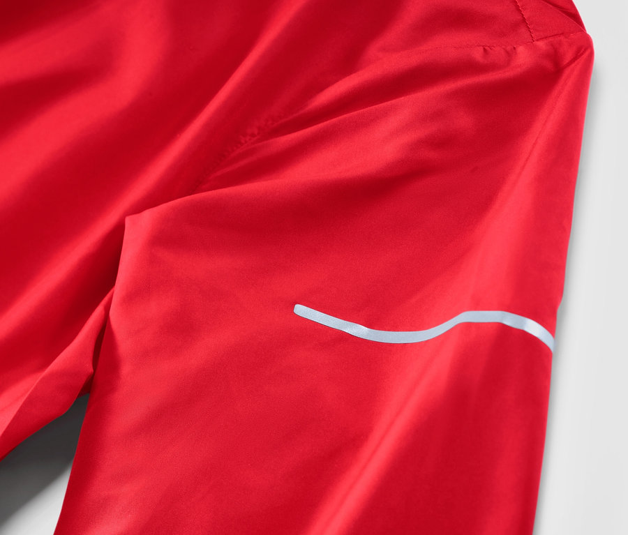 Egy piros női könnyű futódzseki részlete.