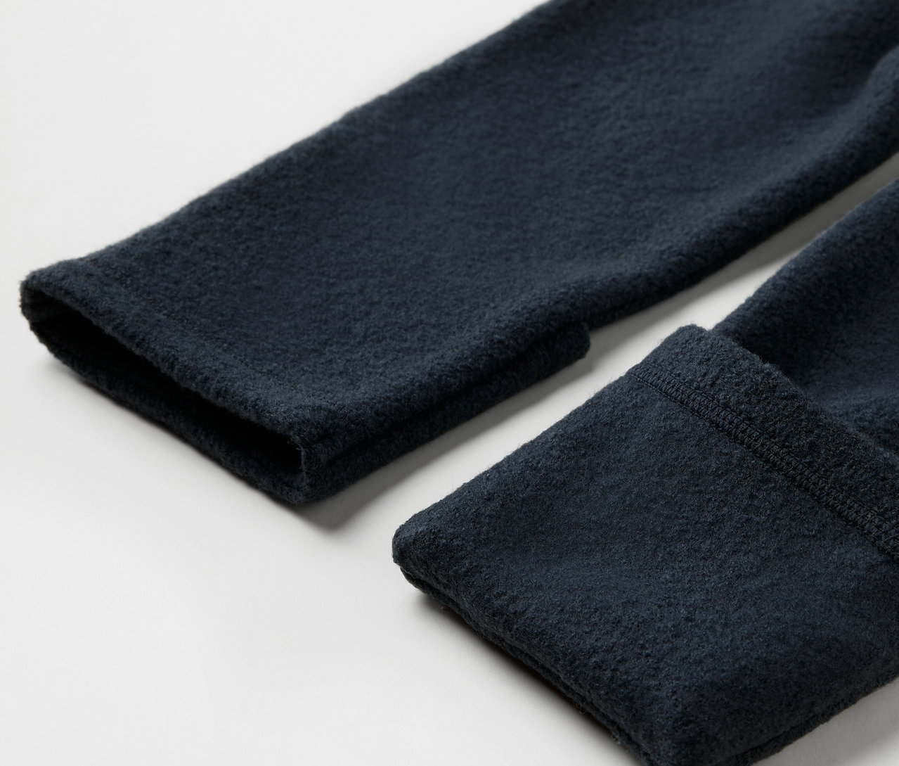 A merinó gyapjúból készült kisgyerek kezeslábas ujja közelről.