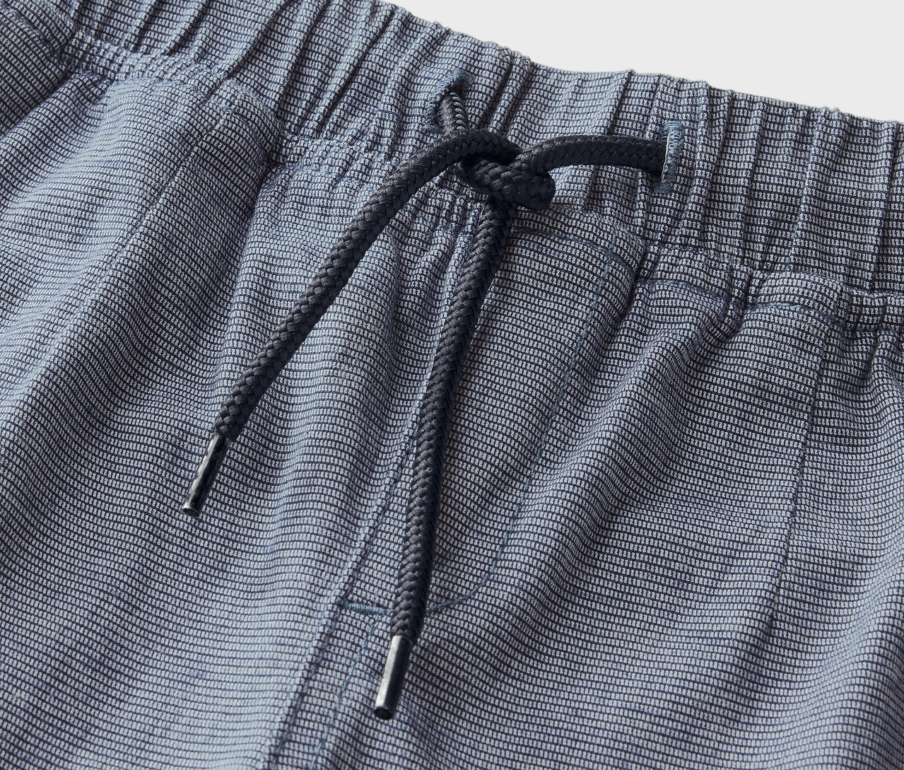 Kék, csíkos rövidnadrág részlete, elasztikus derékpánttal és húzózsinórral.