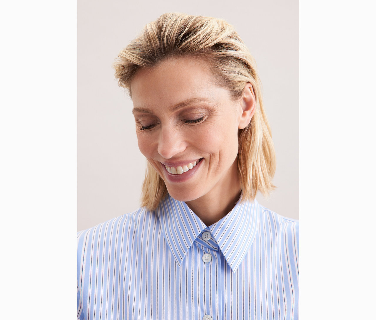 Nő visel egy kék-fehér csíkos Seidensticker túlméretezett ingblúzt.