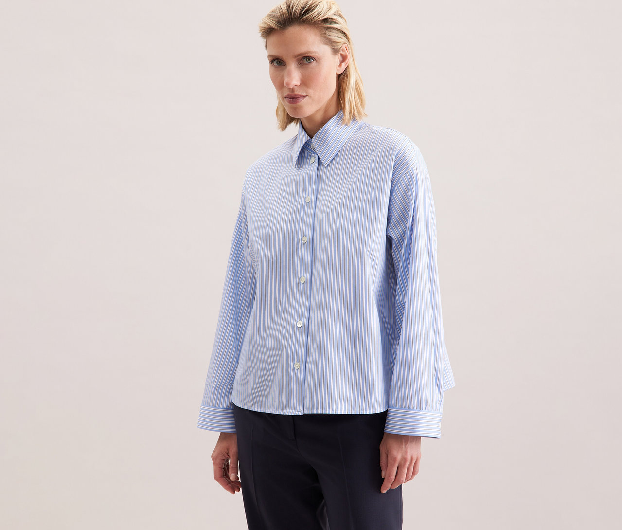 Nő visel egy kék csíkos Seidensticker túlméretezett ingblúzt.