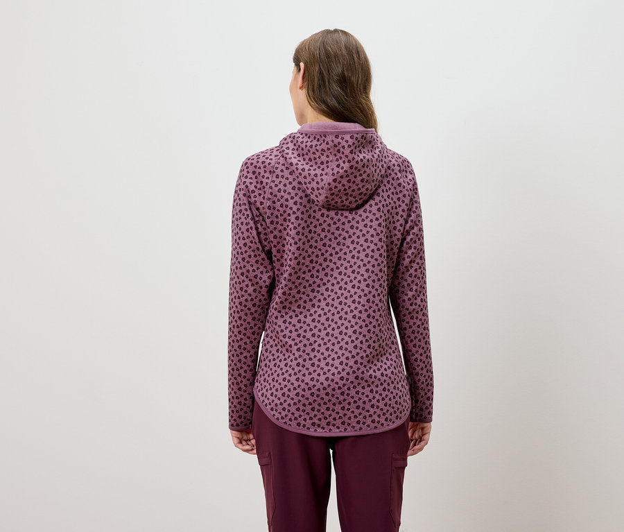 Egy nő hátulról látható, bordó színű, kapucnis tréningruhát visel, állatmintával.