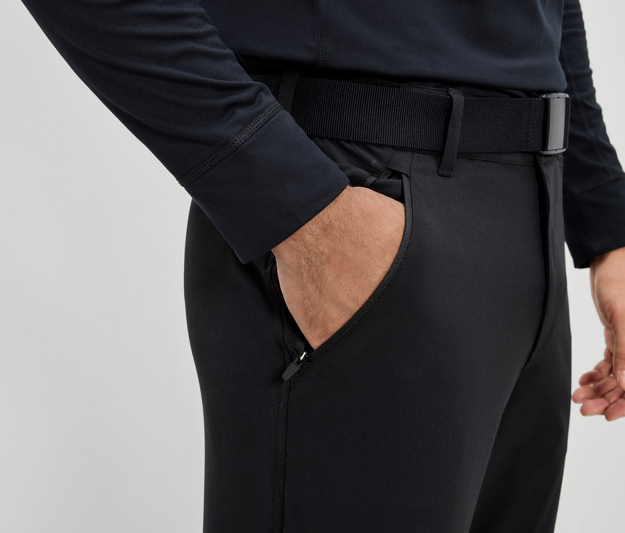 Férfi keze egy fekete öves nadrág zsebében.