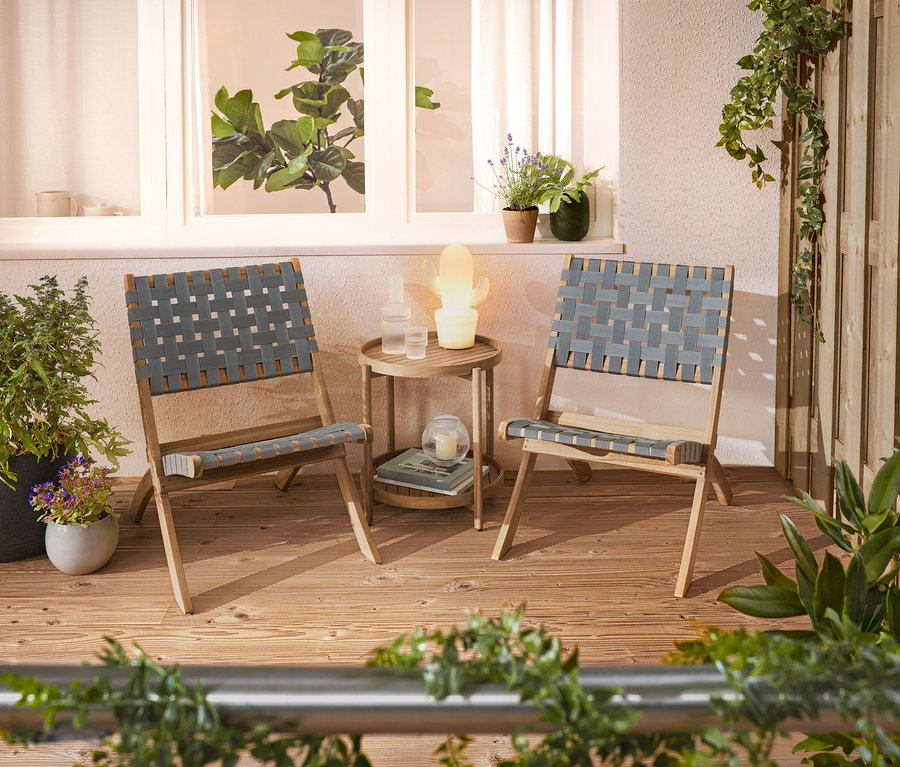Két fonott szék és egy kis asztal áll egy teraszon.