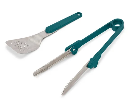 Egy lyukacsos, ezüst színű spatula és egy pár zöld nyelű fogó fekszik egy fehér háttéren.