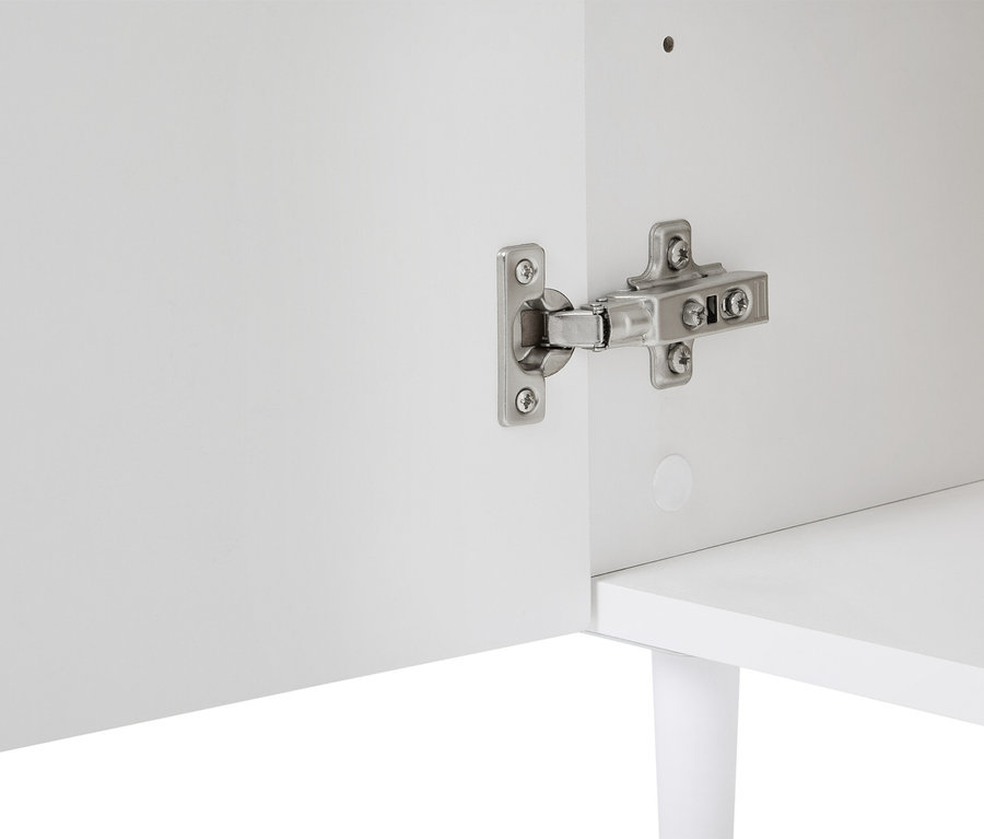 Egy fehér szekrény részletfotója, ezüst színű zsanérrögzítéssel az ajtón.