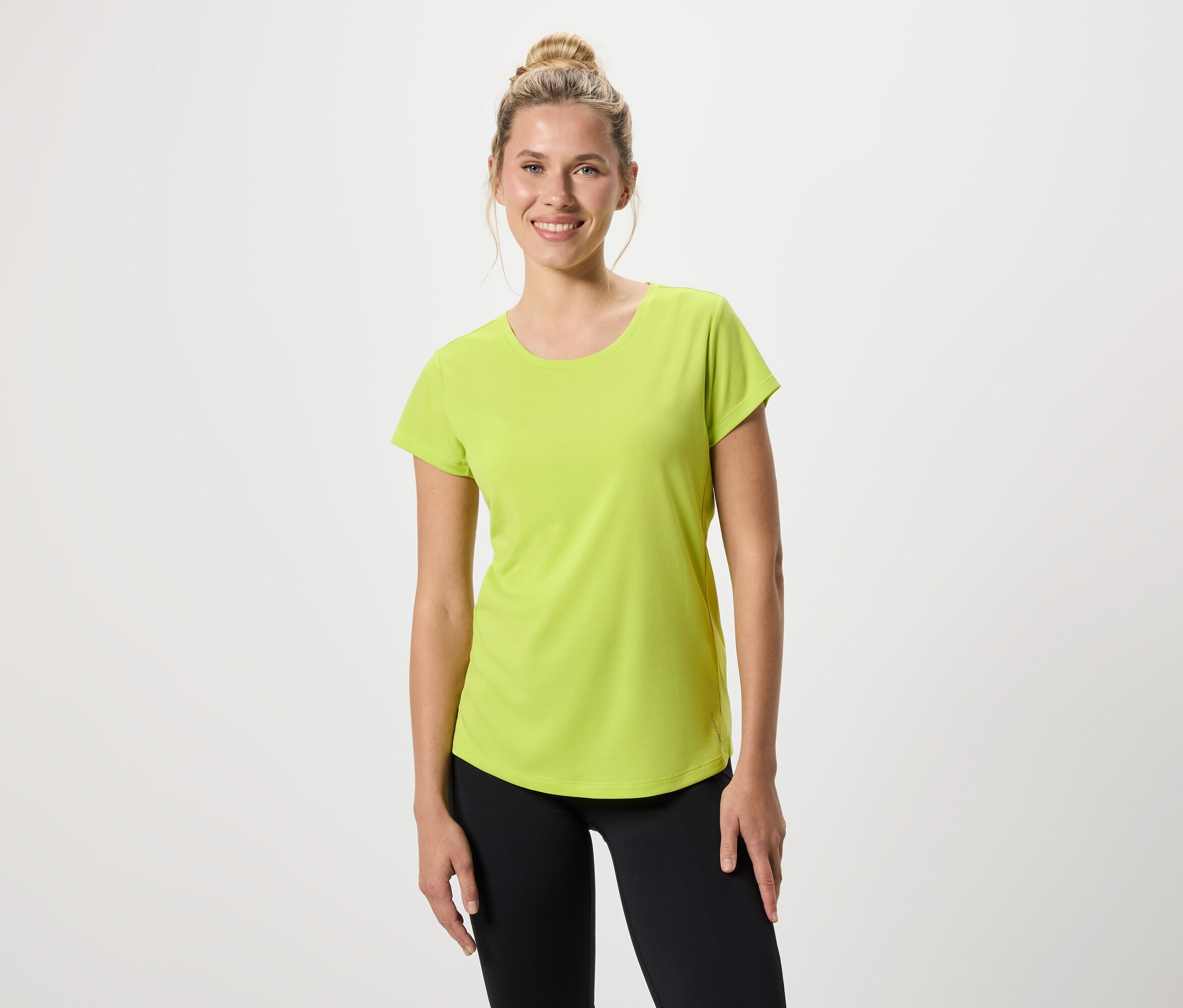 Nő világoszöld pólót és fekete leggingset visel.