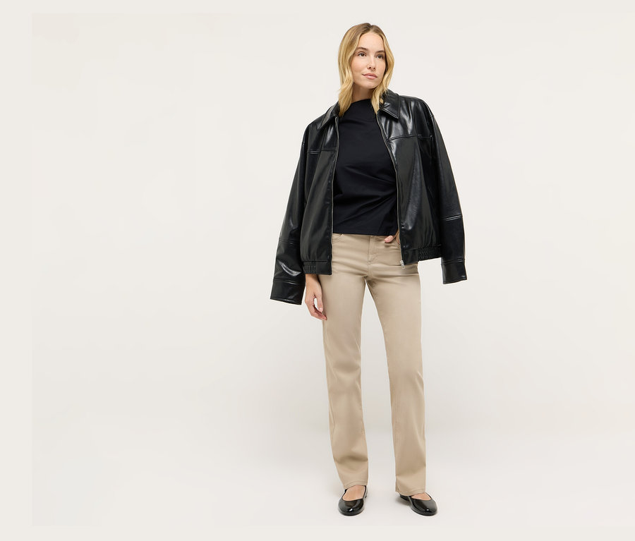 Egy szőke nő áll, fekete kabátot és Angels denim »Lara« egyenes szabású farmernadrágot visel.