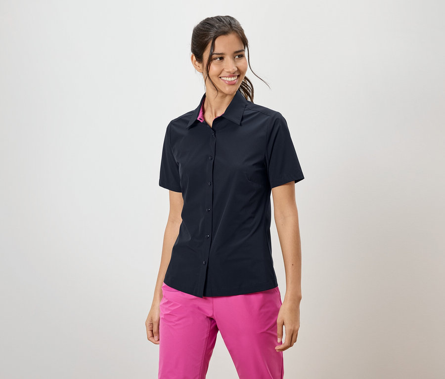 Nő visel sötétkék rövid ujjú inget és rózsaszín nadrágot.