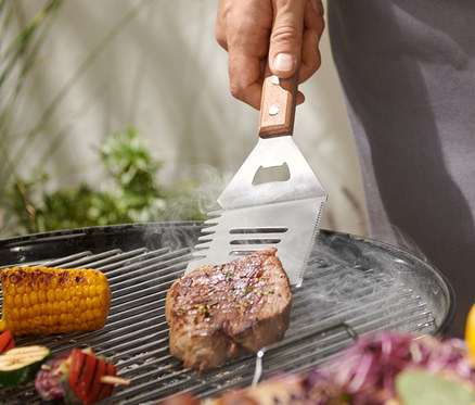 Férfi steaket grillez multifunkciós grillező eszközzel.