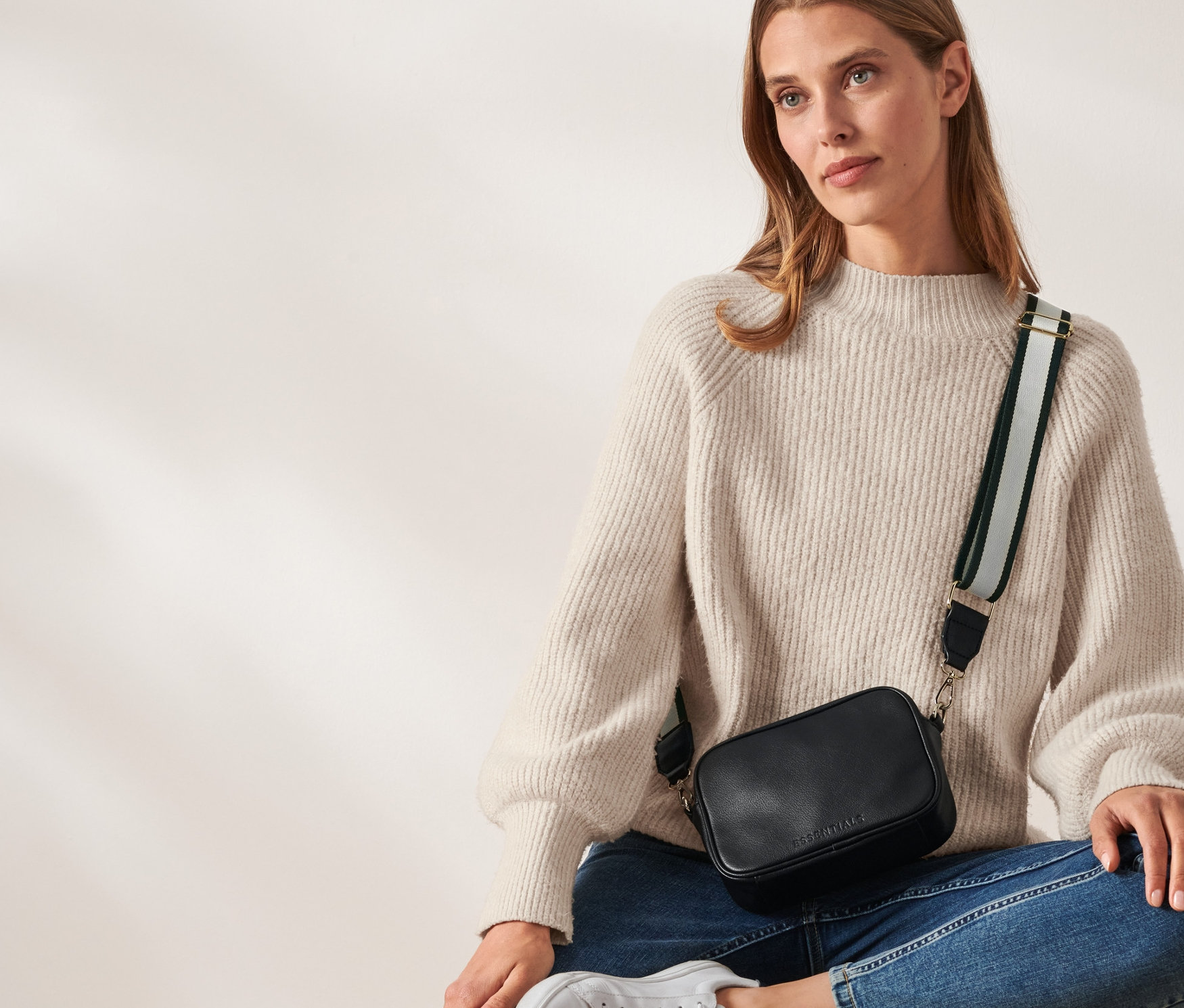 Nő ül egy fa szekrényen és női oldaltáska van rajta.