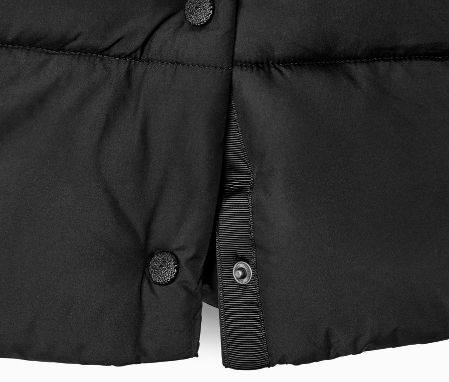 Egy fekete, kapucnis, steppelt kabát részlete gombokkal.