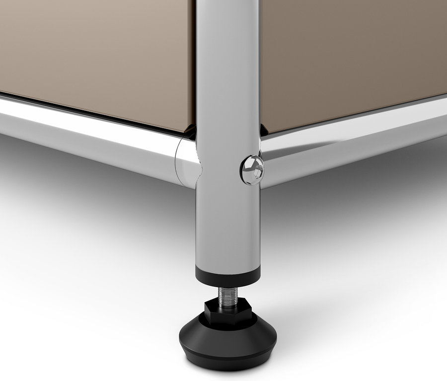 Közelkép egy szürkésbarna fém komód »CN3«-ról, lenyíló ajtókkal, krómozott lábbal és fekete talppal.