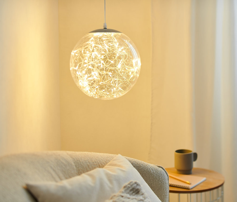 Egy kb. 30 cm-es LED gömb függesztve, megvilágít egy nappalit.