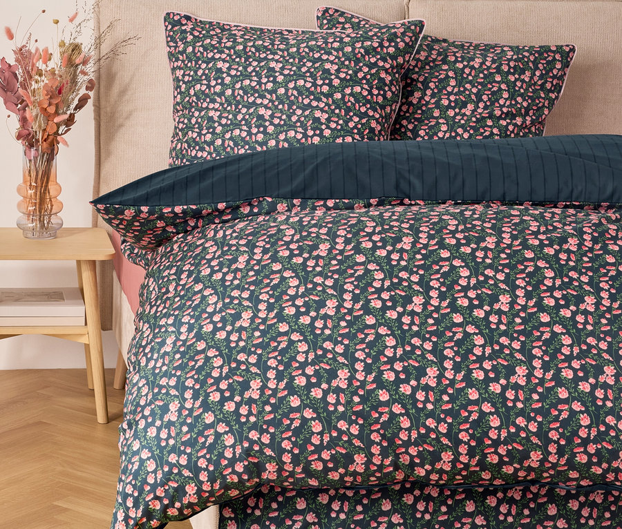 Virágos ágynemű párnákkal egy ágyon.