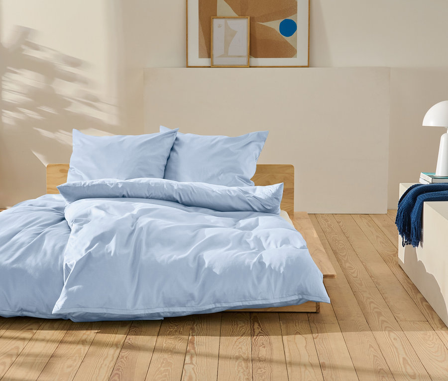 Világoskék ágynemű egy fa ágyon egy hálószobában.